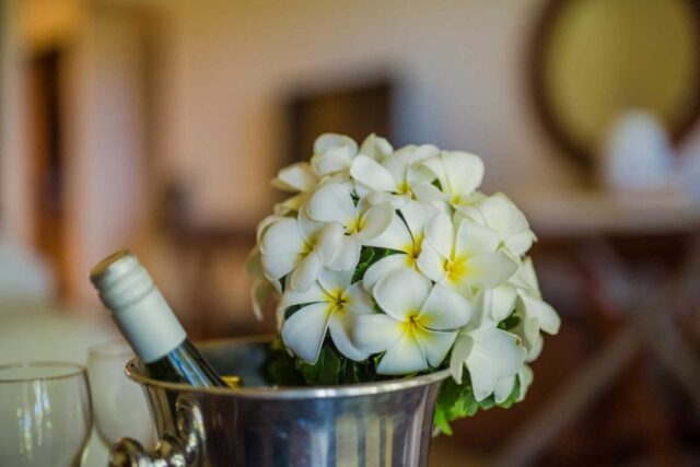 Traum Hochzeit Seychellen, elegante Dekoration mit weißen Blumen und Sektkühler.