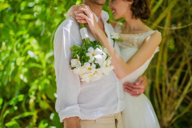 Traum Hochzeit Seychellen, romantisches Brautpaar mit Blumenstrauß in tropischer Natur.